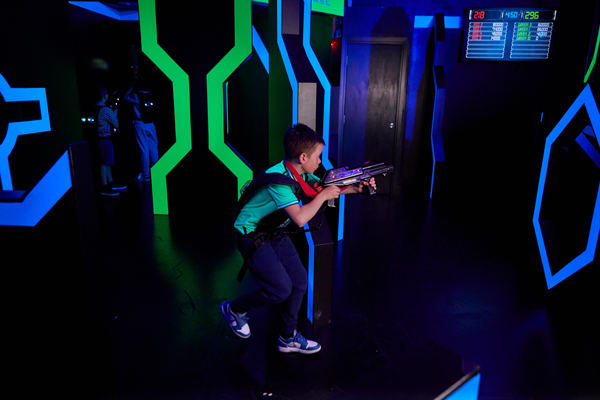 Young boy getting ready to attack with his laser gun in laser tag arena